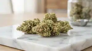 Cogollos secos de cannabis Ak x Somango Auto con abundante resina sobre superficie de mármol.